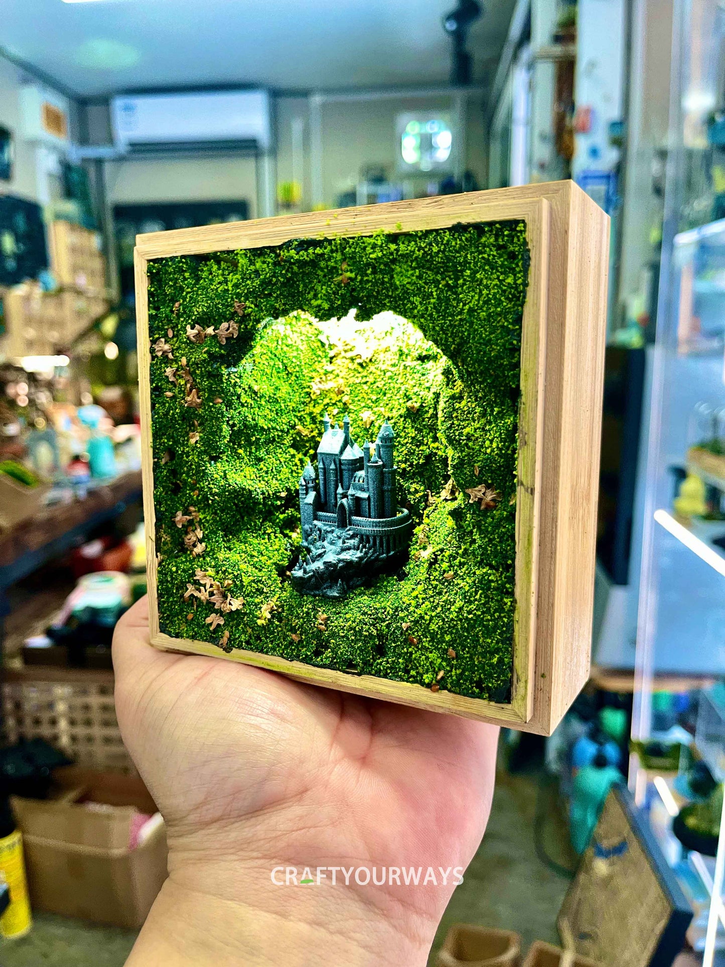 Miniature Castle in Illuminated Cave with Greenery in Wooden Box