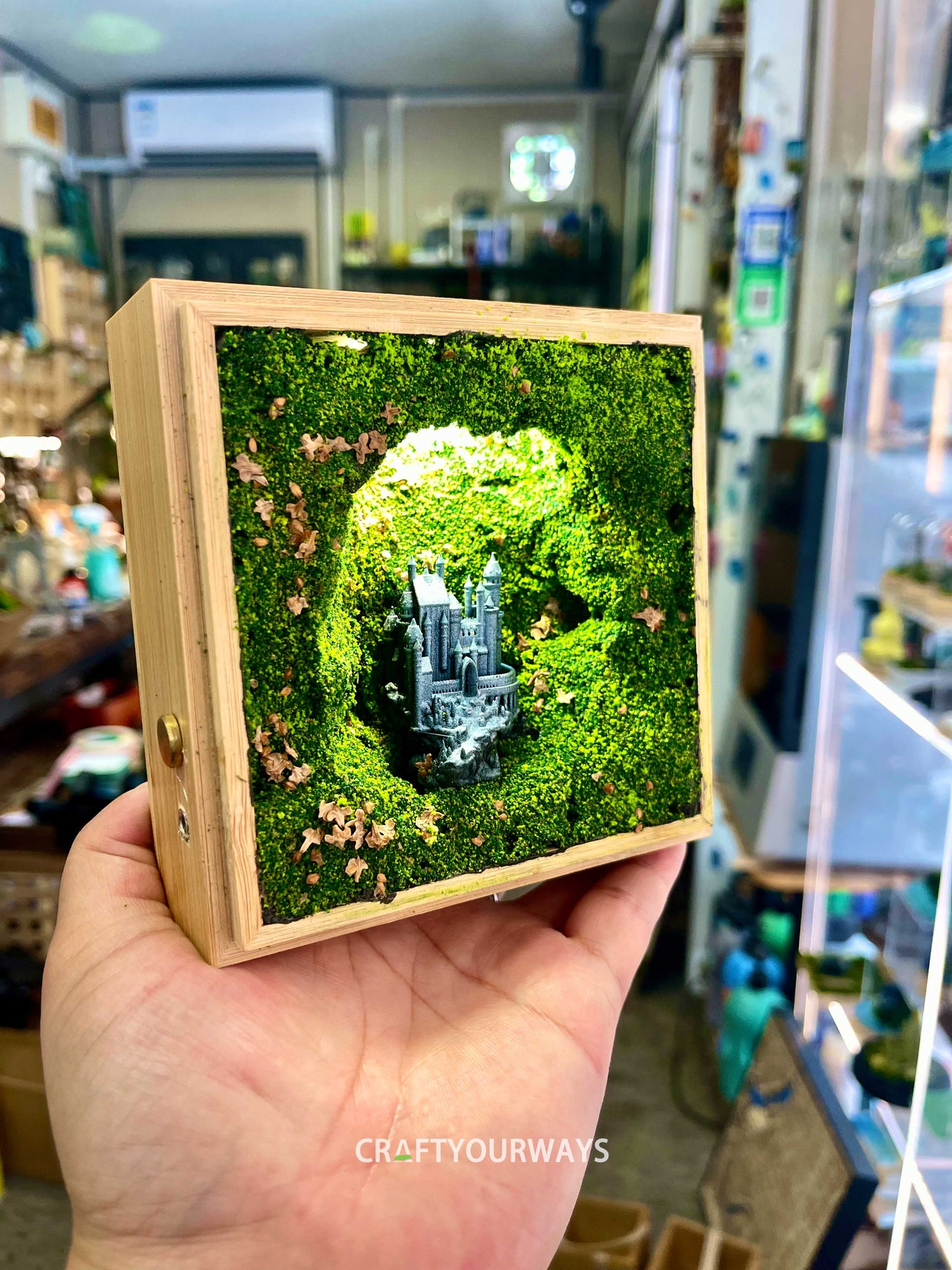 Miniature Castle in Illuminated Cave with Greenery in Wooden Box