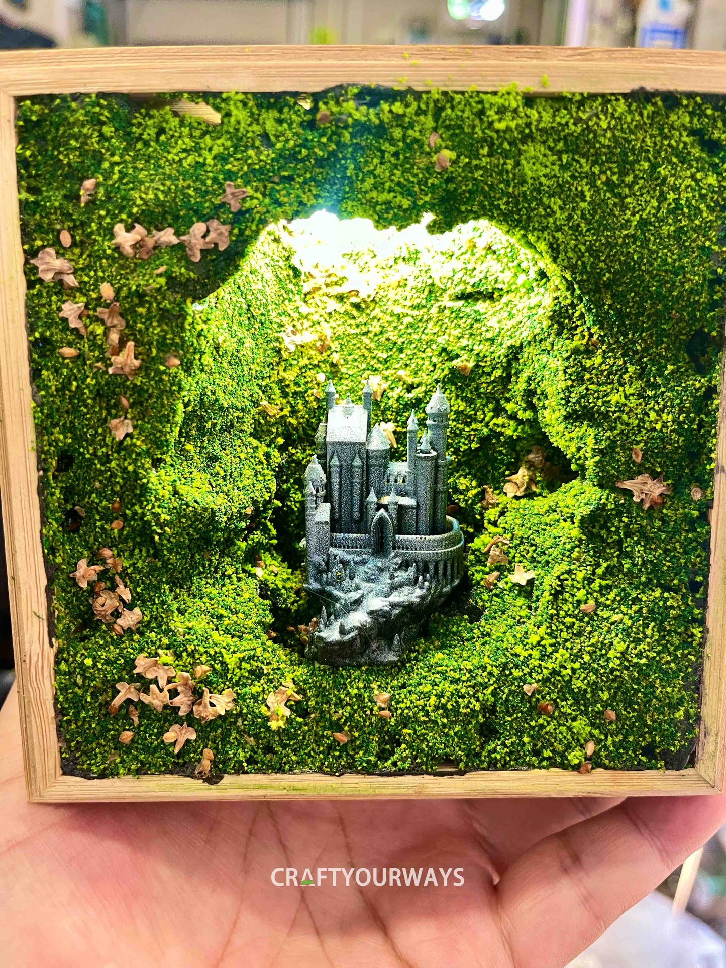 Miniature Castle in Illuminated Cave with Greenery in Wooden Box